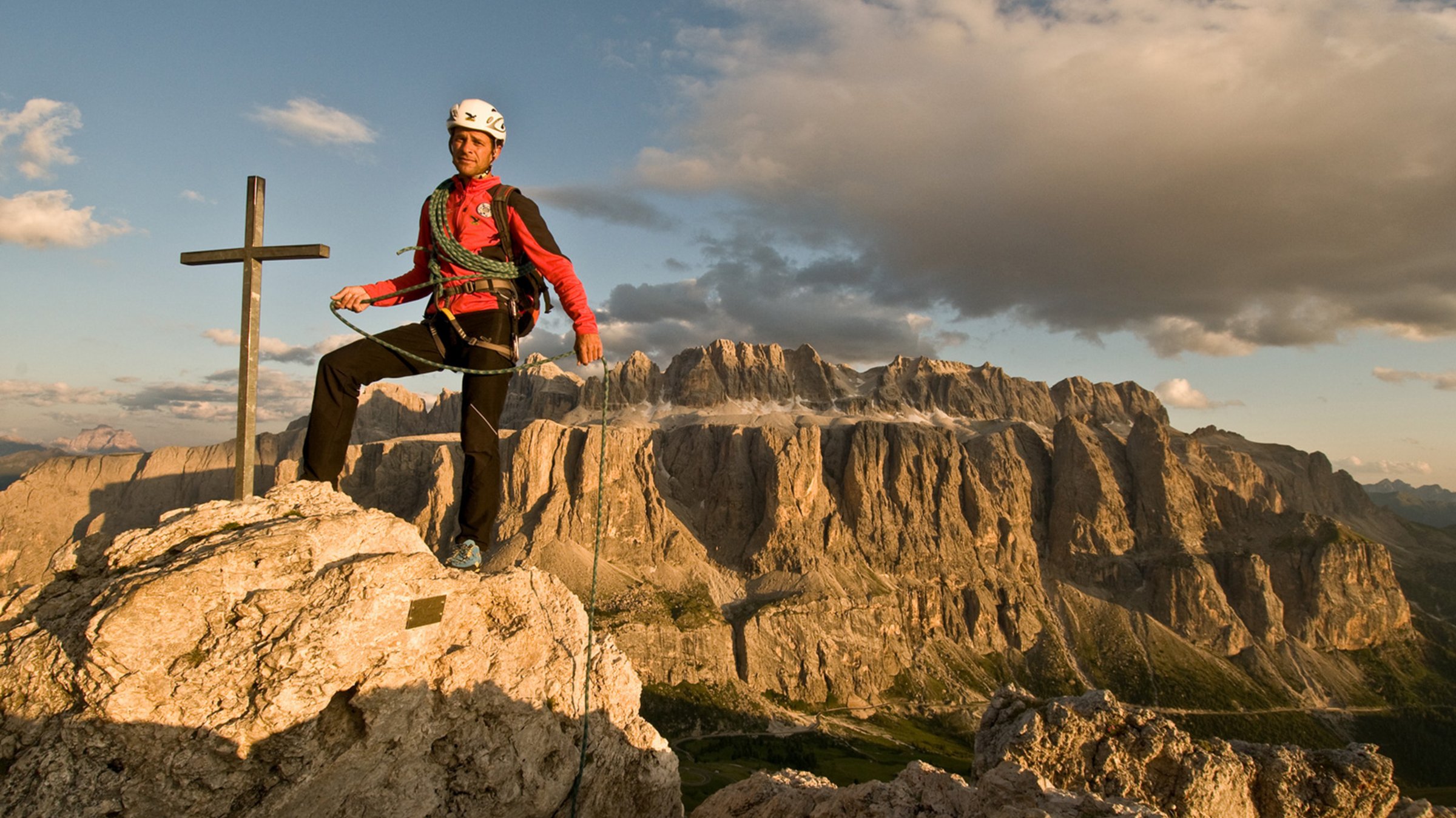 Mann hat das Gipfelkreuz in den Dolomiten erklettert